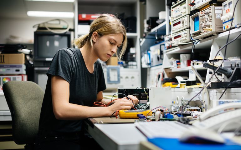 Young female engineer measuring voltage on a conductor board in her workshop