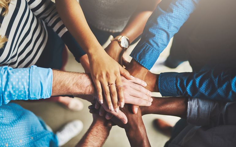 Shot of a group of creative businesspeople standing with their hands in a huddle
