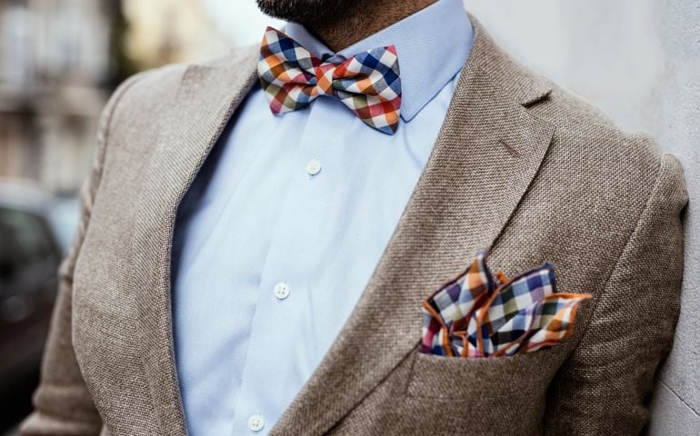 Close up of well dressed man's torso. Guy wearing jacket, shirt and colorful handkerchief and bow tie