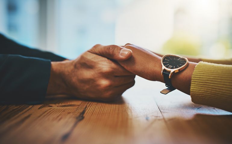 Cropped shot of a man and woman compassionately holding hands at a table