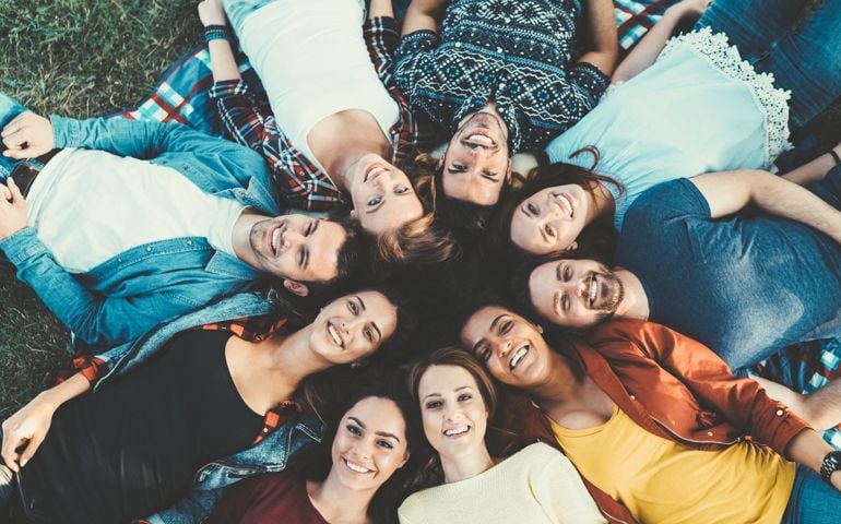 Above view of young people lying down in a circle and looking at camera