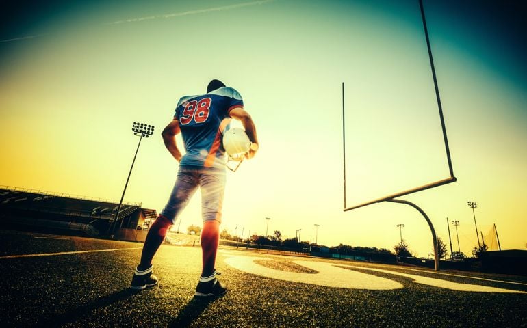American Football Player standing on football field at down.