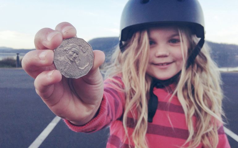 Child holding out silver coin that she found on the ground