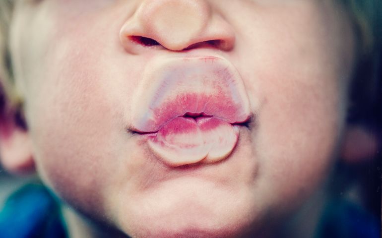 Little boy squashing his mouth against the glass to blow a kiss