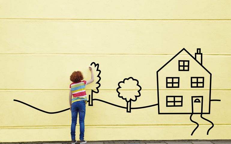 Girl drawing a house and trees onto a wall