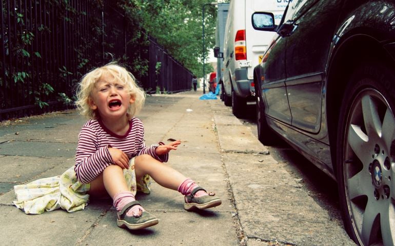 Small girl having a tantrum on the pavement.