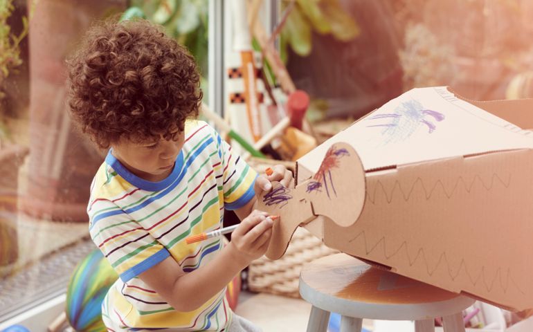 Boy playing with cardboard aeroplane