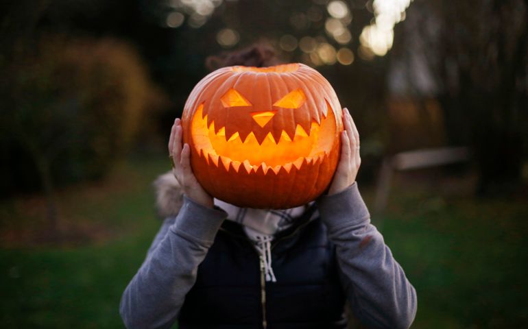 A girl with Halloween pumpkin in front of her head