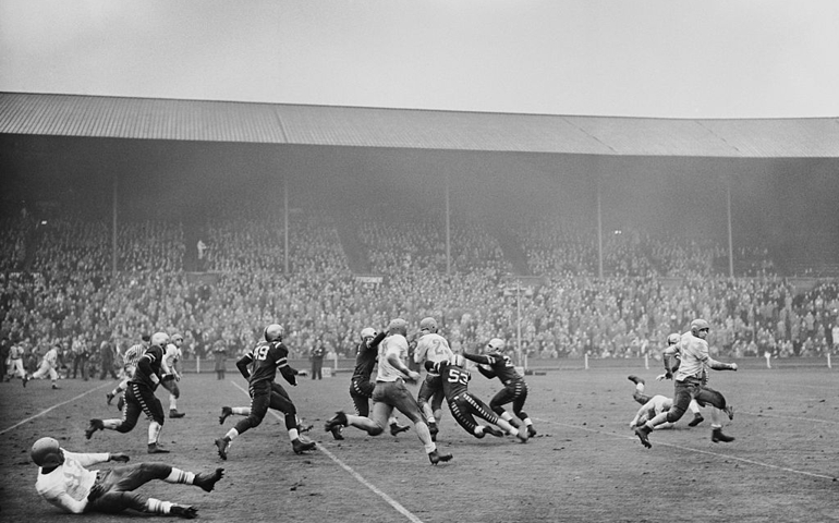 A player makes a tackle during the American Air Forces in Europe Football Championship final between the Burtonwood Bullets and Fuerstenfeldbruck Eagles at Wembley Stadium, 13th December 1952.