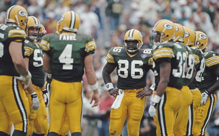 Quarterback Brett Favre #4 of the Green Bay Packers talks to his offensive line in the huddle as Tight End Ed West #86 looks on during the National Football Conference Central game against the Minnesota Vikings on 4 September 1994 at Lambeau Field, Green Bay, Wisconsin, United States. The Packers won the game 16- 10.