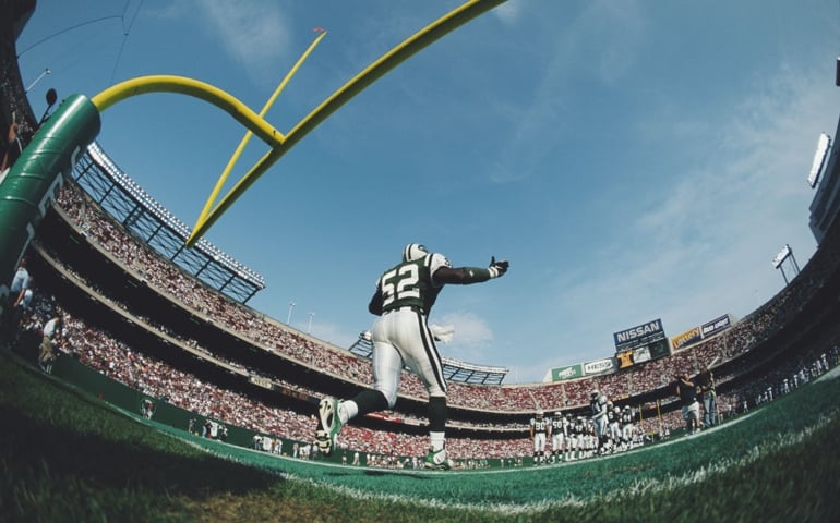 Pepper Johnson #52, Linebacker for the New York Jets runs onto the field beneath the goal posts during the introduction to the American Football Conference East pre season game against the Baltimore Ravens on 15 August 1998 at the Meadowlands Stadium, East Rutherford, New Jersey, United States. The Ravens won the game 33 - 0.