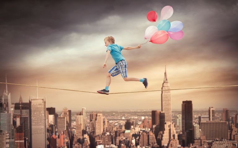 Young boy running with balloons on the rope over New York city