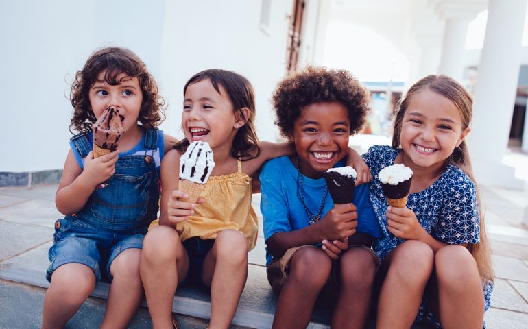 Multi-ethnic best friends children eating ice-cream and having fun on summer holidays