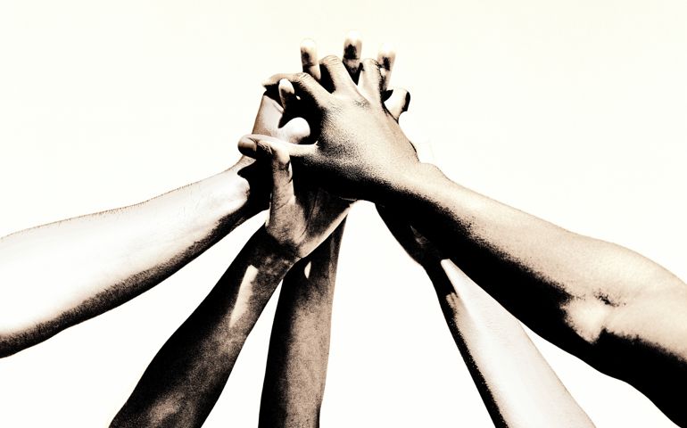 Group of young people's hands clasped together (toned B&W)