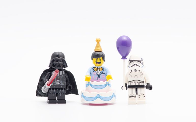 lego darth vader with party cake man and storm troopers holding a balloon