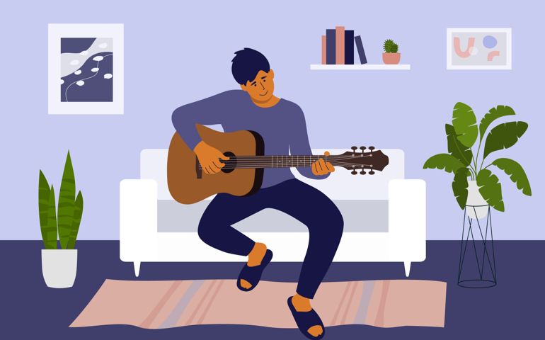 Guy sitting on sofa in living room learning to play on musical instrument