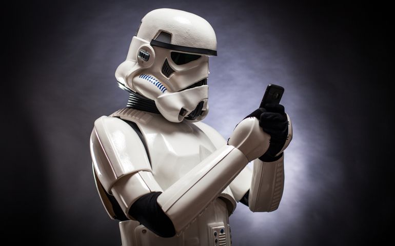 Funny studio portrait of stormtrooper costume replica with a mobile phone