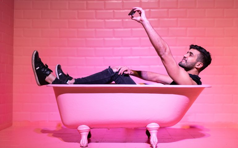 Man Taking a Selfie in a pink bath tub