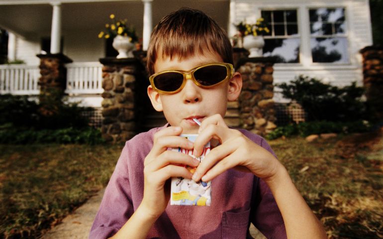 Boy on porch steps drinking juice box