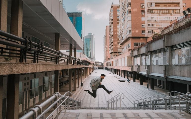 A young man taking a big jump in a city street