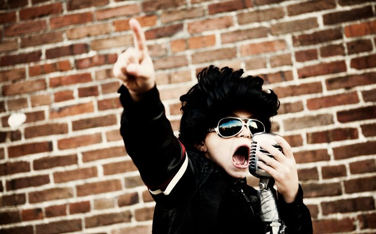A young boy inspires the crowd dressed up as Elvis Presley.