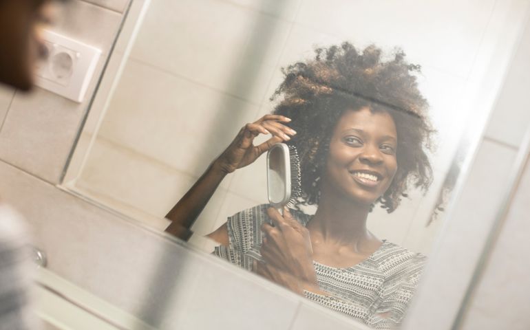 Young woman fixing her hair. About 25 years old, African female.