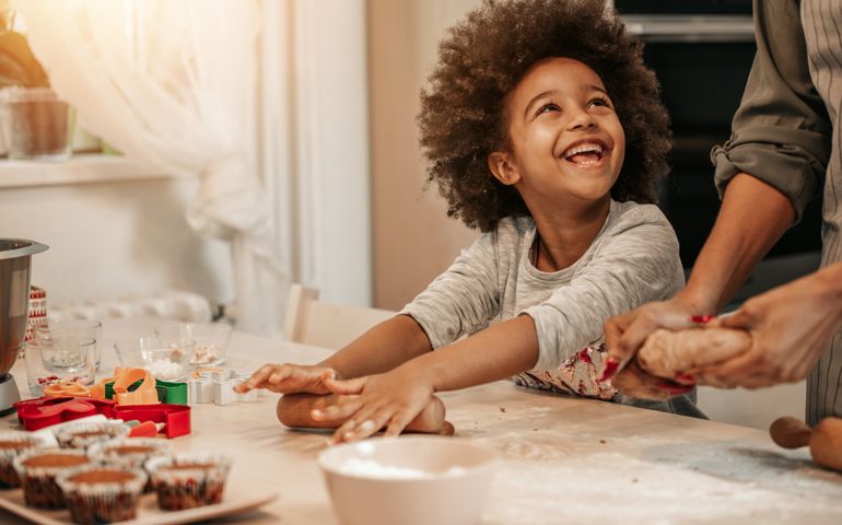 Cute 5 years old girl making cookies for Christmas with her mom.