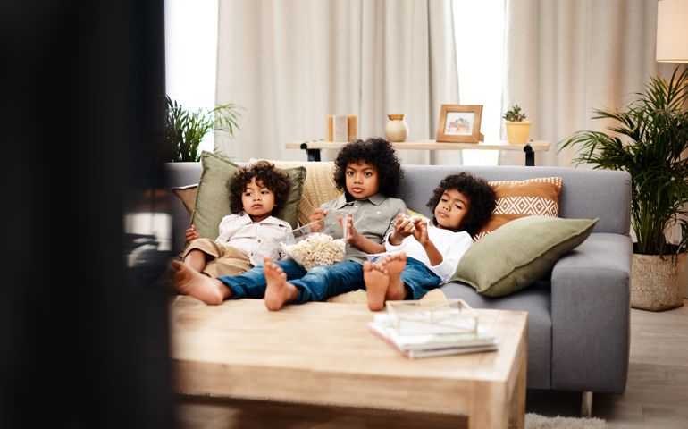Full length shot of three adorable little boys eating popcorn and watching movies together at home