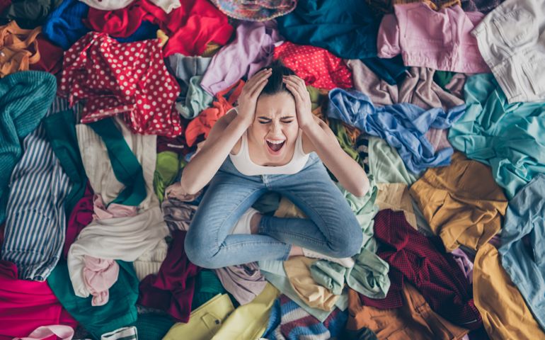 Help. High angle above view photo of stressed yelling lady stay home spring, cleaning household sit many clothes stack floor pick select look outfit nothing to wear hands on head indoors