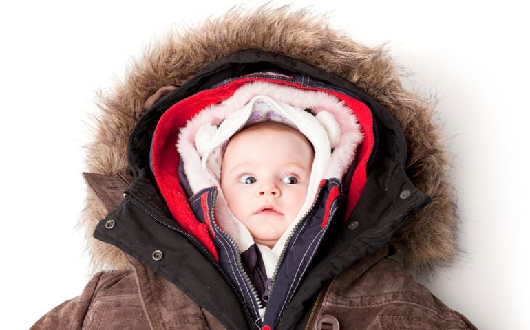 Concept portrait of a cute 3 month baby girl in many winter jackets.