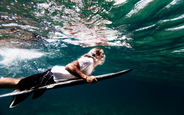 Surfer duck diving under reef break