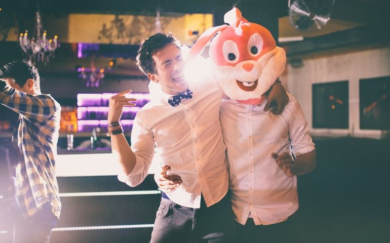 Guy standing next to a friend wearing a bunny head, singing along to the music in a night club