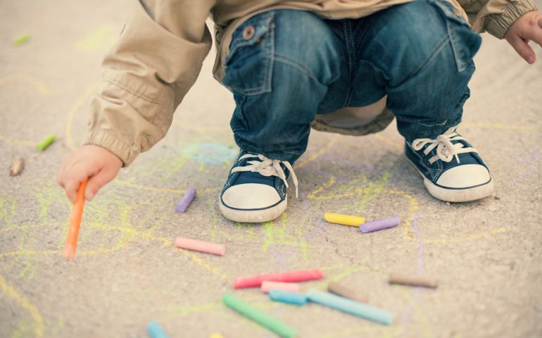 Little boy drawing with sidewalk chalks. Shallow depth of field