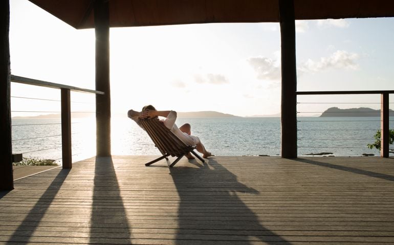 Woman relaxing in deck chair on veranda.