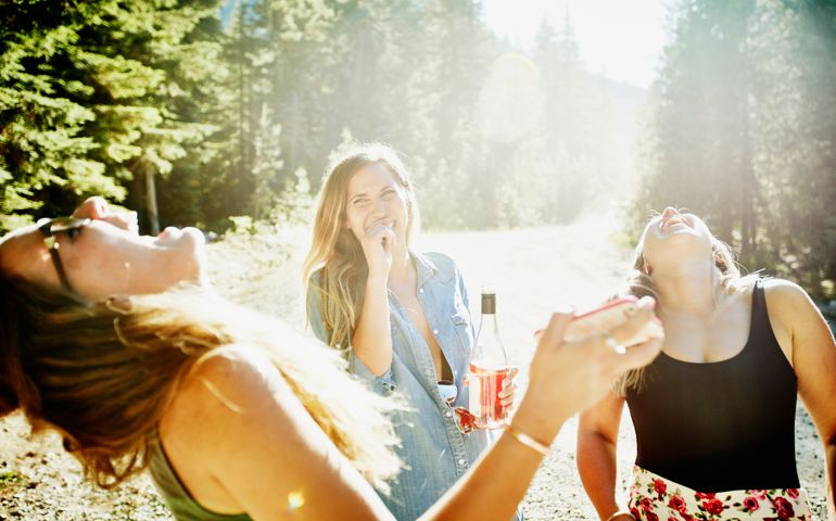 Female friends on vacation laughing together and sharing wine on summer afternoon