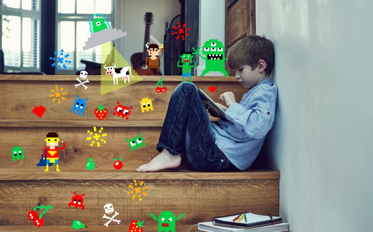 Boy playing on digital tablet with game symbols