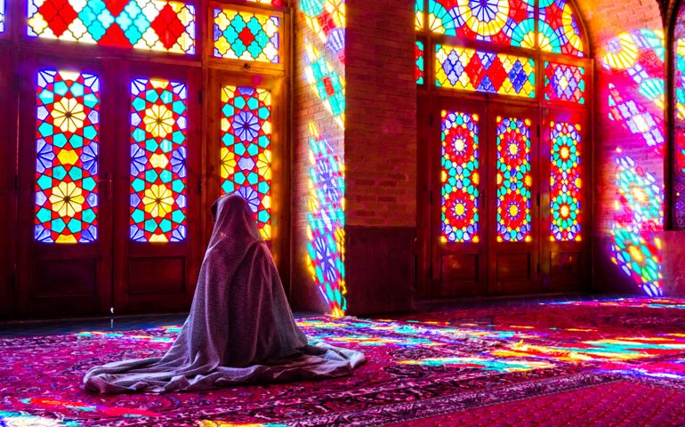 Worshipper in front of stained glass windows of Prayer Hall, Nasir-al Molk Mosque, Shiraz, Iran
