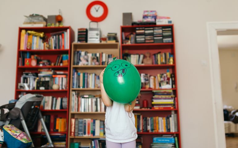 A photo of a young girl hiding behind a balloon