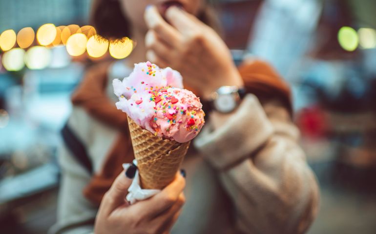 Happy teenager eating ice-cream in the city in the evening