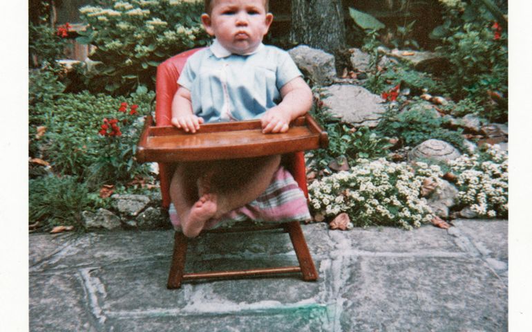 Baby boy sitting in his highchair in garden.