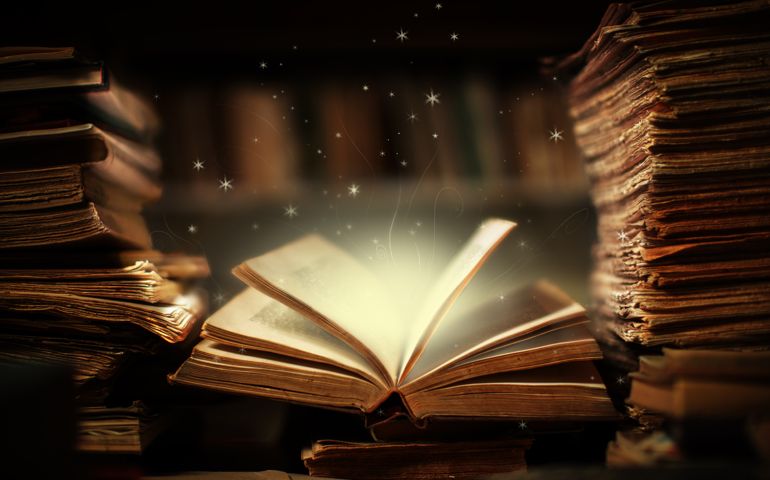 Magical book lying open on desk in library. Stars and shapes flying from glowing pages and illuminates surrounding. Fairy brush made from my own drawing.