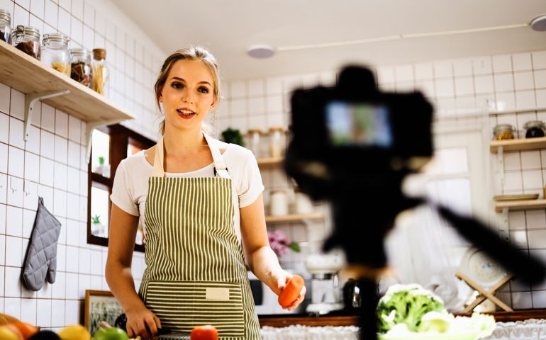Beautiful young girl blogger live cooking at kitchen for working from home. COVID-19