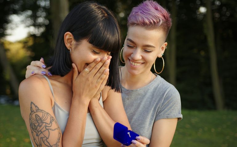 Pretty woman proposing to her girlfriend to get married and smiling