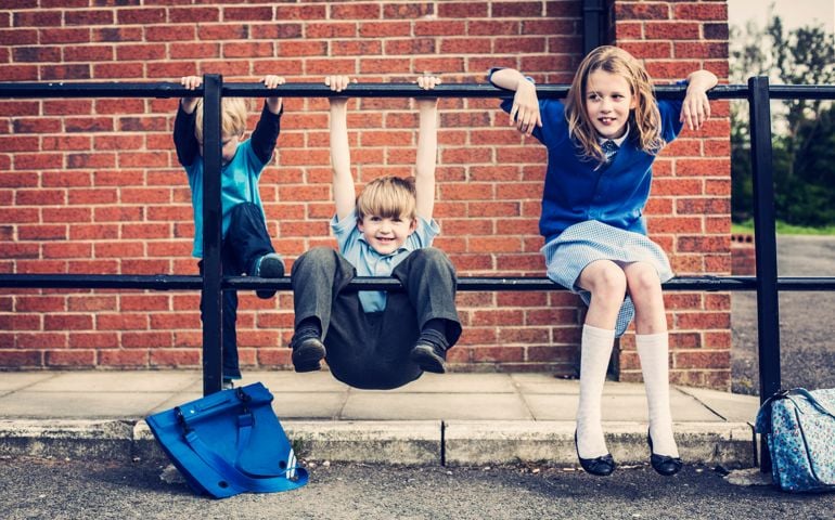 Three school children waiting outside school.