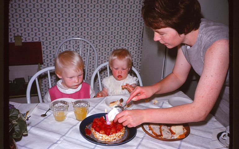 Mother and daughters celebrating 1st birthday with cake and one candle on it.
