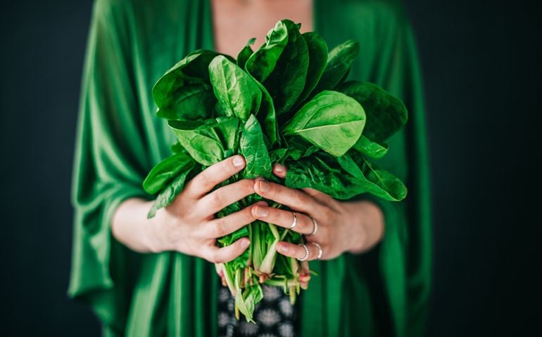 Young woman holding spinach leafs salad
