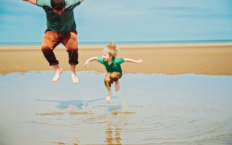 Father and little boy having fun, jumping in the sea together