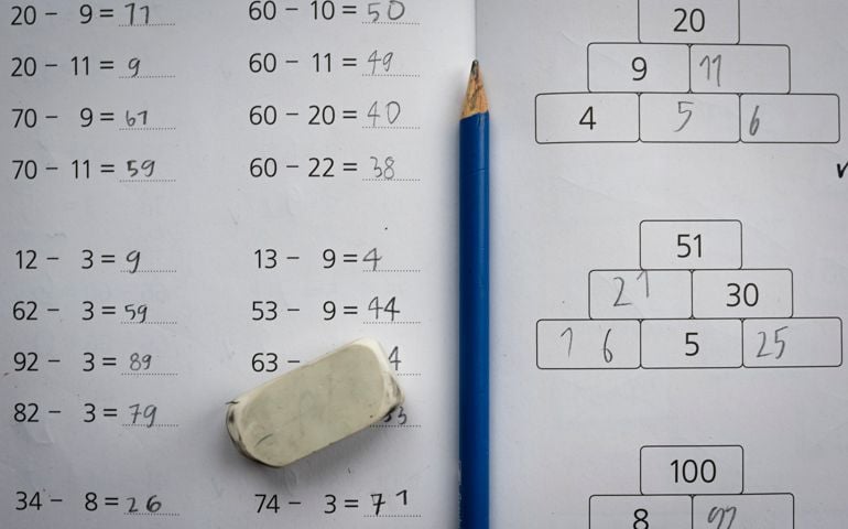 Close-up of a pencil and eraser on an elementary school mathematics exercise book with arithmetics exercises.