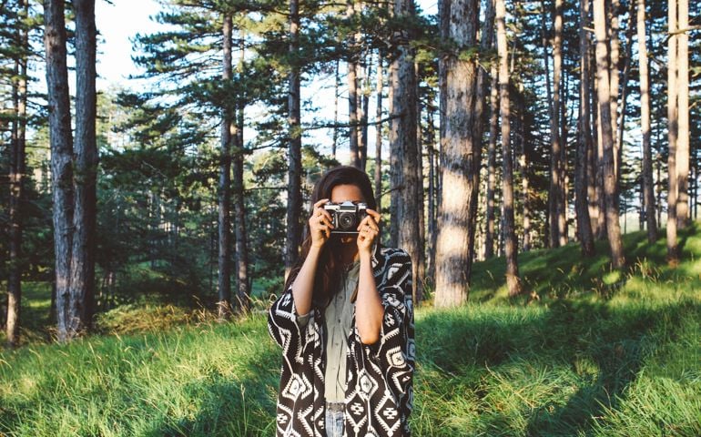 Forest in Dinaric Alps, mountain range in Southern Europe, on the border of Croatia and Bosnia. Young woman is walking, taking photos and enjoying her time and freedom in the nature.