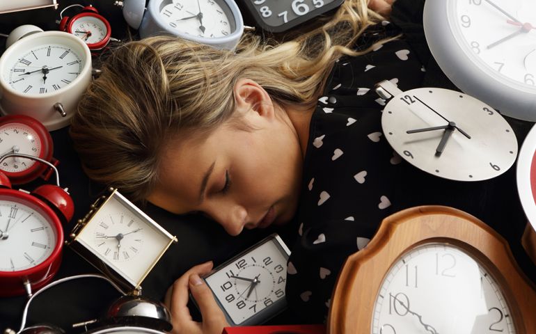 woman asleep surrounded by clocks